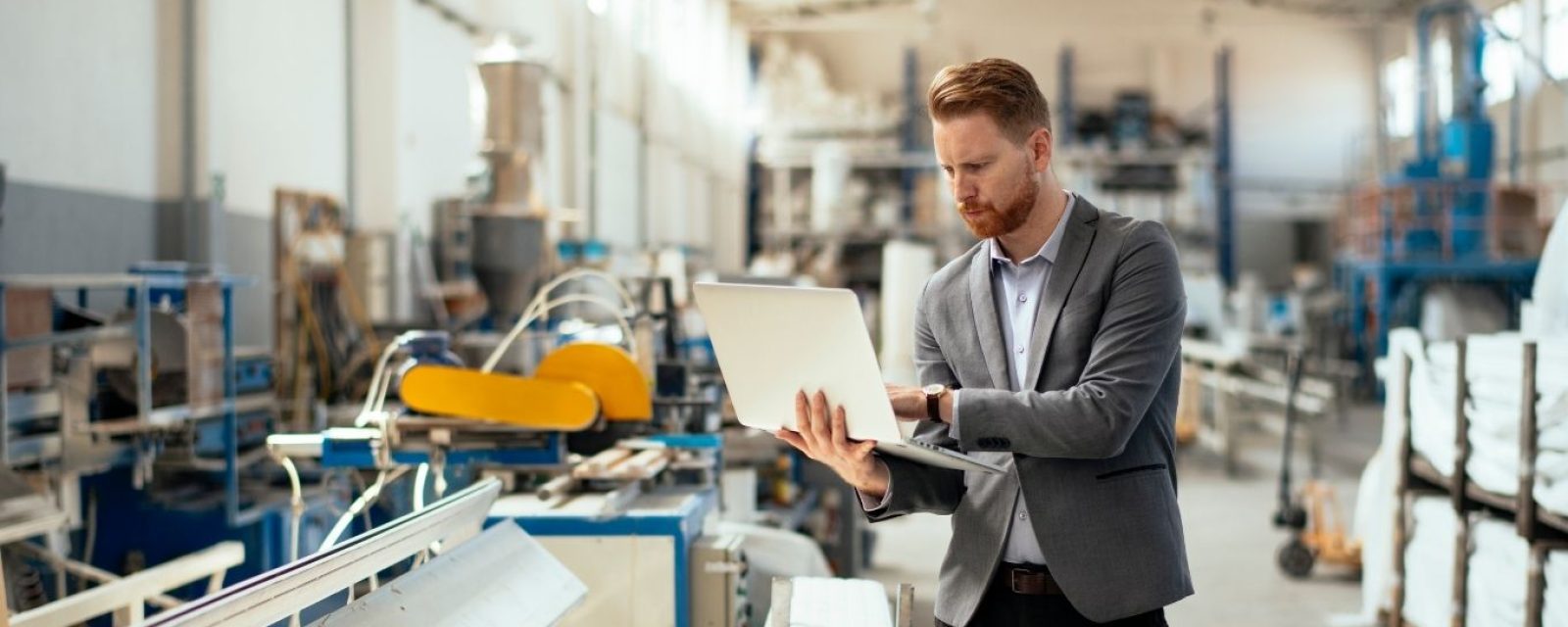 Business man in manufacturing building holding a laptop