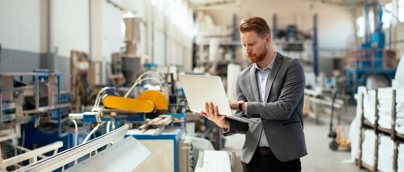 Business man in manufacturing building holding a laptop