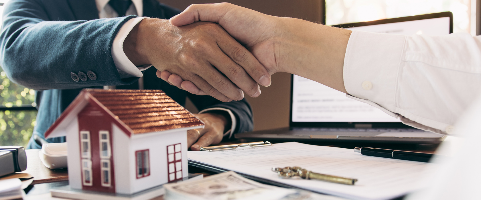 Loan officer shaking hands with a client that is looking to buy a house.