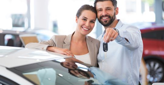 Happy couple holding the keys to their new car
