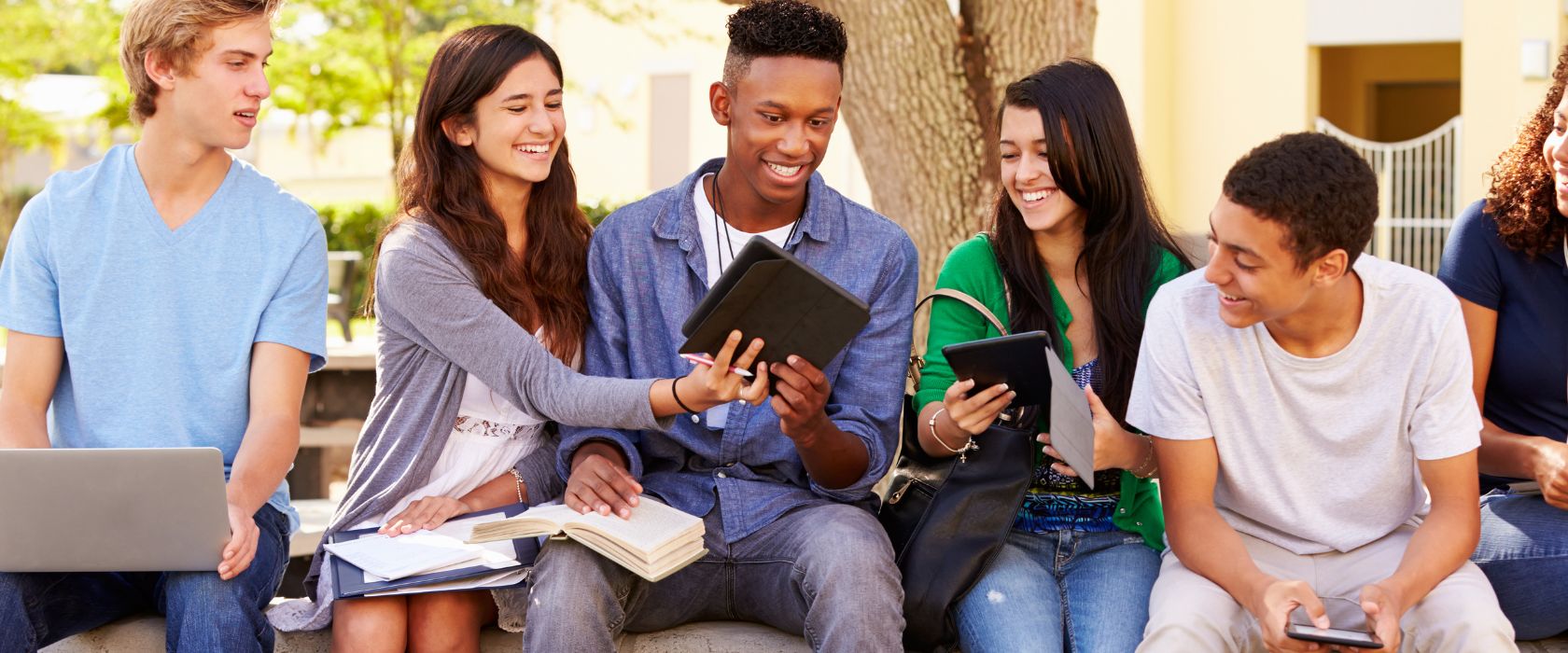 Group of high school students sitting outside with homework