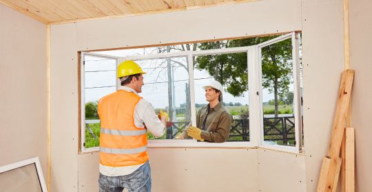 Construction workers installing new windows in a home
