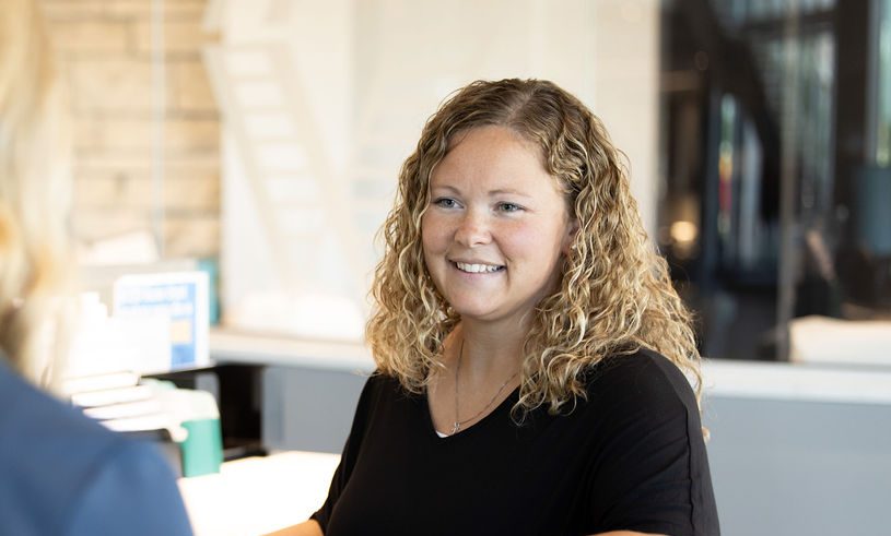 Smiling Midwest Bank employee helping a client at the teller desk