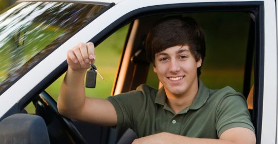Highschool boy holding the keys to his first car