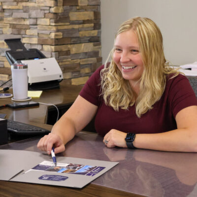 Tanisha Brahmer at the Pilger branch sitting at her desk helping a client.