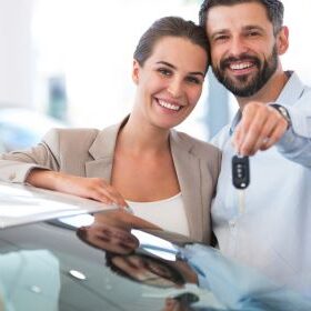 Happy couple holding the keys to their new car