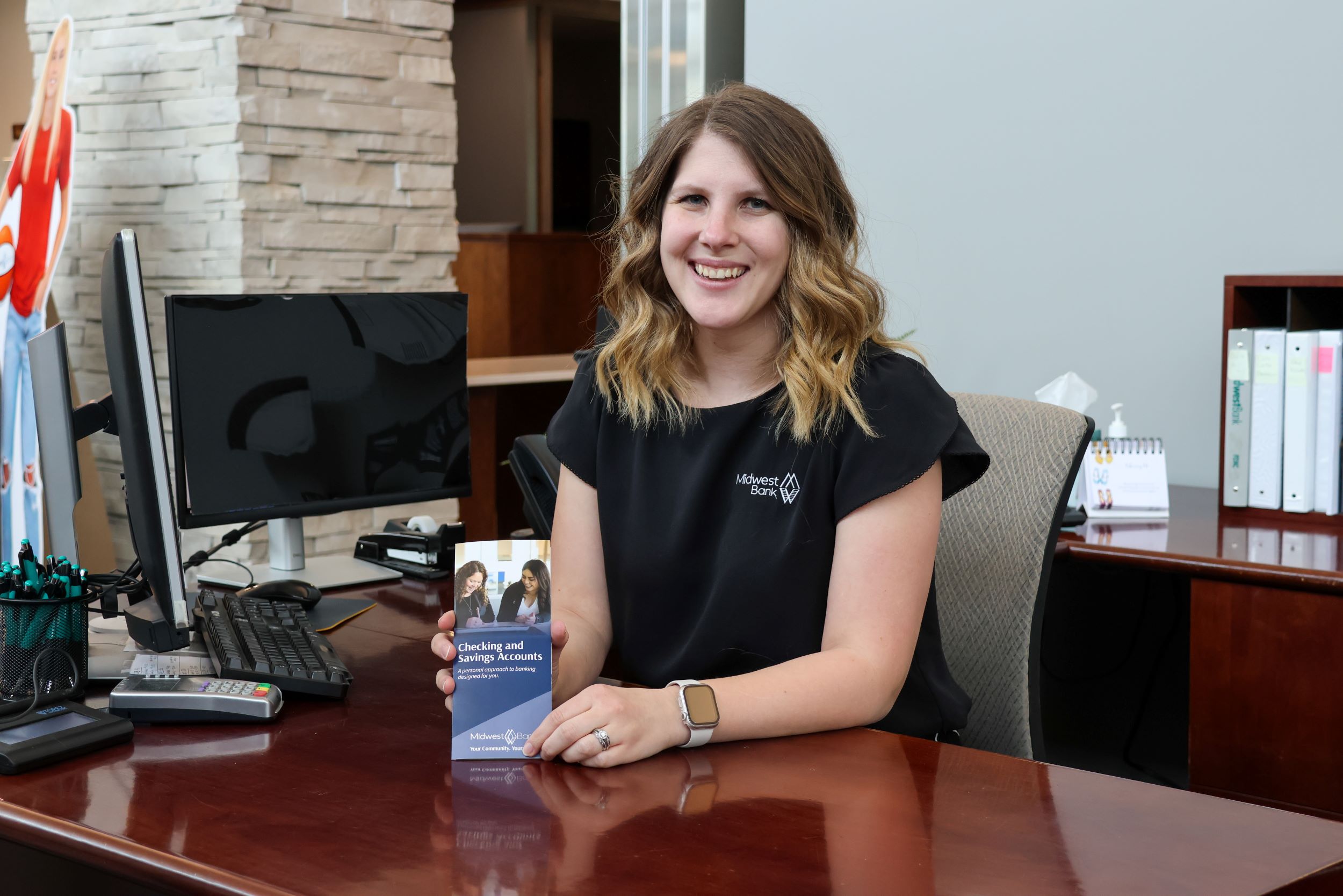 Daisha. retail banking manager, at Pierce branch sitting at her desk holding a brochure